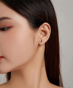 Close-up of a s925 gold-plated bee stud earring with black enamel on a female ear