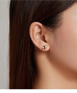 Close-up of a s925 silver bee stud earring with gold plating and enamel on model's ear