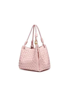 Pink hand-woven bucket bag with golden metal knot detail and chic braided handle