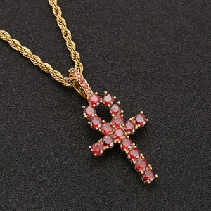 Macro shot of gold rope chain with Ankh cross pendant set with red zircons