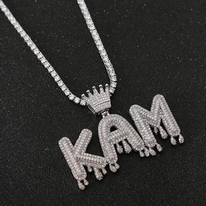 Macro detail of iced-out KAM letter pendant with crown and tennis chain in silver