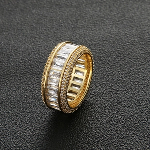 Macro view of gold hip-hop ring with emerald-cut zircon and pave-set crystals