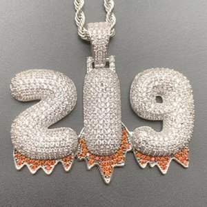 Detail of hip hop number 219 pendant necklace with white zircons and orange drip effect