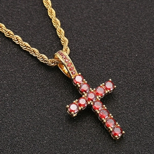 Detail of hip hop gold rope chain with a red zircon encrusted cross pendant on black