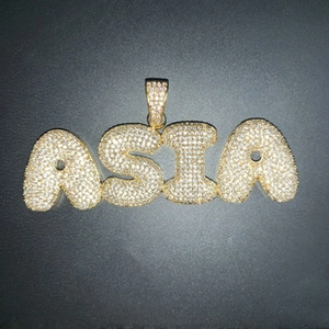 Macro shot of hip hop ASIA bubble letter pendant with gold plating and paved white zircons