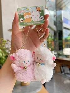 Close-up of pink and white plush lamb pendants with gold bell chains and gift tags
