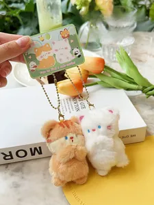 Detail of magnetic plush cat keychains in white and orange with metal chains and packaging
