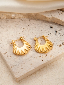 Macro shot of gold-plated stainless steel earrings with grooved texture on stone surface