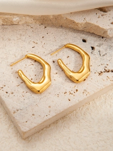 Detail of gold titanium steel earrings featuring irregular molten lava texture and u-shape