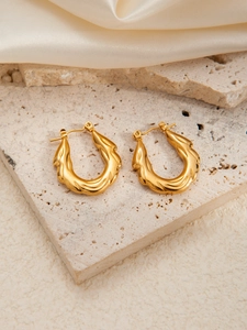Detailed macro view of gold-tone titanium earrings with unique twisted shell texture details