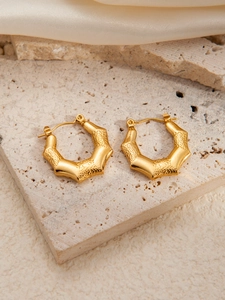 Detailed macro view of gold-plated hexagonal bamboo texture earrings on stone background