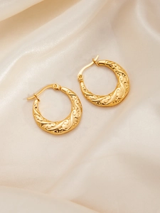 Nahaufnahme goldener Edelstahl-Ohrringe mit geprägtem floralem Vintage-Muster
