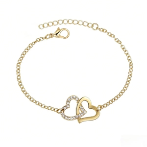 Détail du bracelet doré avec double cœur entrelacé serti de cristaux et fermoir mousqueton