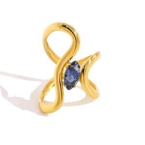 Macro detail of wave-shaped gold ring featuring marquise-cut navy blue gemstone inlay