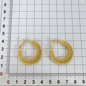 Detailed size measurement of golden woven textured hoop earrings on a grid scale