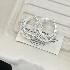 Macro detail of silver woven bead texture on minimalist round hoop earrings