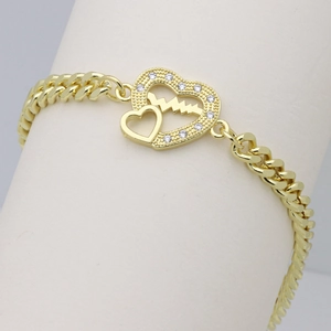 Close-up of golden Cuban chain bracelet with heart pendant and heartbeat pulse line