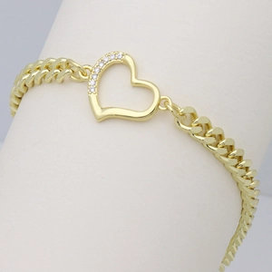 Detail view of a gold Cuban link bracelet with a sparkling zircon-studded heart pendant