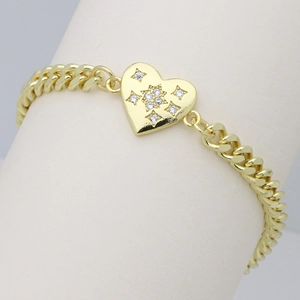 Detailed macro view of gold Cuban chain bracelet featuring a star engraved heart charm