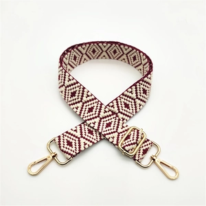 Close-up of adjustable woven shoulder strap with burgundy geometric patterns and gold clips
