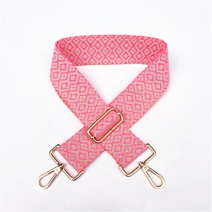 Detail of adjustable pink and beige geometric woven wide shoulder strap with gold clips
