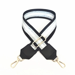 Close-up of black and silver striped adjustable shoulder strap with gold lobster clasps