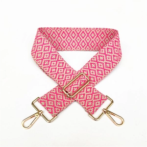Close-up of ethnic style woven bag strap with rose pink geometric pattern and gold clasps