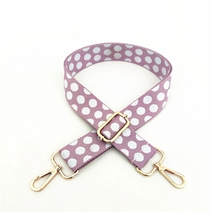 Close-up of adjustable purple polka dot shoulder strap with gold metal swivel hooks