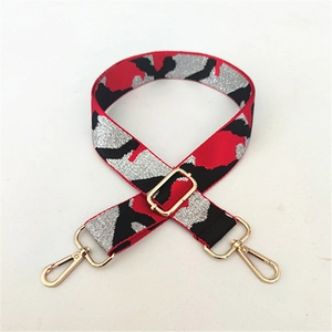 Detail of camouflage fabric shoulder strap with golden metal swivel hooks and adjuster