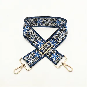 Close-up of ethnic style wide strap with blue geometric embroidery and gold hardware