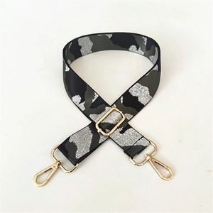Macro shot of adjustable camouflage bag strap with premium gold metal swivel snap hooks