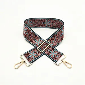Close-up of ethnic woven adjustable shoulder strap with floral patterns and gold metal clips