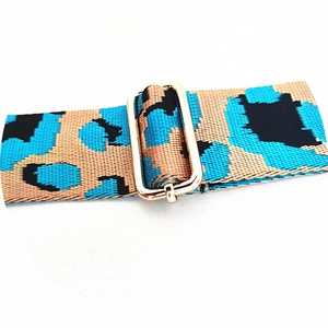 Detail of adjustable leopard print bag strap featuring a polished gold metal buckle
