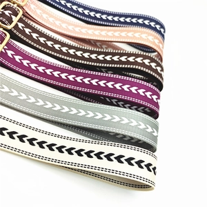 Detail of adjustable woven bag straps with geometric chevron patterns and gold metal hardware