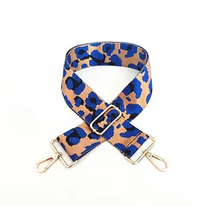 Detail of adjustable leopard print bag strap with shiny gold lobster clasps and blue pattern