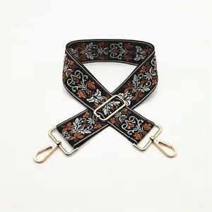 Close-up of ethnic style wide guitar strap for bags with floral embroidery and gold hooks
