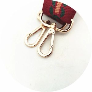 Detail of red and green striped woven bag strap with polished gold lobster clasp