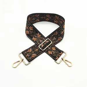Close-up of ethnic jacquard purse strap with gold floral patterns and metal buckles