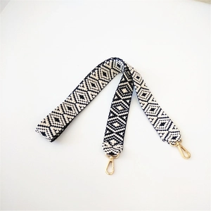 Adjustable woven shoulder strap with black and white geometric pattern and gold clasps