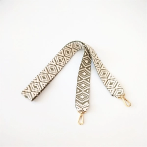 Detail of woven geometric jacquard bag strap with emerald green pattern and gold lobster clasps