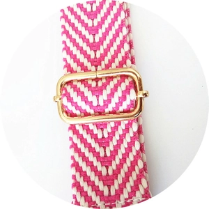 Detail of rose pink and white woven bag strap with adjustable gold buckle component