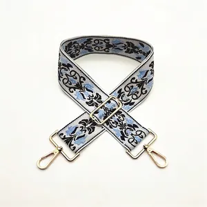 Close-up of ethnic blue floral embroidery on adjustable wide grey shoulder strap with gold clips