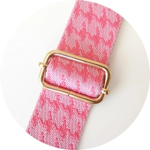 Detail of pink houndstooth strap with golden metal rectangular adjustable buckle
