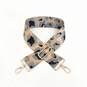 Detail view of adjustable wide leopard print bag strap with polished light gold metal buckles