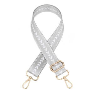 Detail view of adjustable woven shoulder strap with white arrows and gold metal hooks