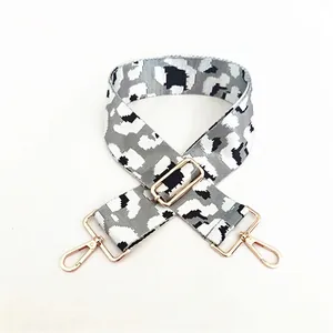 Macro view of adjustable wide leopard print bag strap with golden metal swivel snap hooks