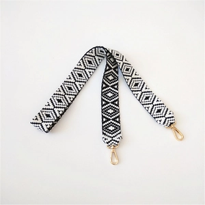 Detail of woven black and white geometric pattern bag strap with gold metal swivel hooks