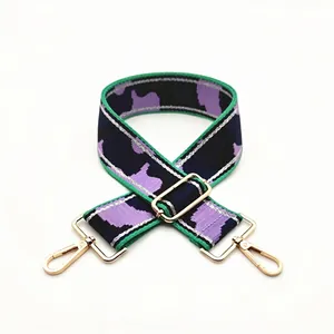 Detail of adjustable camouflage nylon strap with purple green tones and gold hooks