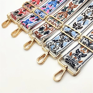 Close-up of five ethnic embroidery bag straps with golden metal hooks and adjustable buckles