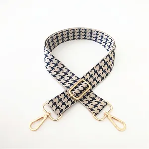 Close-up of houndstooth replacement bag strap with adjustable gold-tone metal buckles